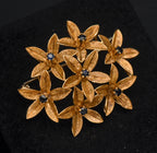 Stunning vintage antique handcrafted 18k gold brooch consisting of seven flowers with florentine finish, each set with a round cut sapphire.